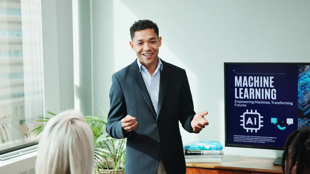 Een professionele man in pak geeft een presentatie over machine learning en AI voor een publiek, met een groot scherm waarop de tekst "MACHINE LEARNING: Empowering Machines, Transforming Futures" te zien is, als illustratie bij een artikel over carrièremogelijkheden in de kunstmatige intelligentie.
